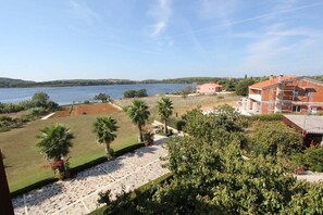 Vista di una proprietà con giardino curato, palme e uno specchio d'acqua sullo sfondo.
