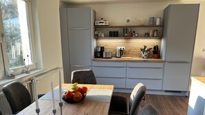 A modern kitchen with grey cabinets, a wooden countertop, and a dining area with a table set for four. - Apartment with Private Terrace, Shared Garden, and Wi-Fi in Heringsdorf (Heringsdorf)