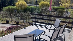 A patio with a table and chairs, surrounded by a wooden deck and a view of trees and a forest. - Apartment with Private Terrace, Shared Garden, and Wi-Fi in Heringsdorf (Heringsdorf)