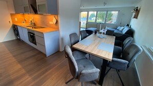 A modern kitchen with a central island, dining area with chairs, and a sofa in a living space. - Apartment with Private Terrace, Shared Garden, and Wi-Fi in Heringsdorf (Heringsdorf)