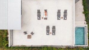 An aerial view of a rooftop terrace with a pool, lounge chairs, and a small table. - NELBLU FLAMINGO SUITES (Playa Flamingo)