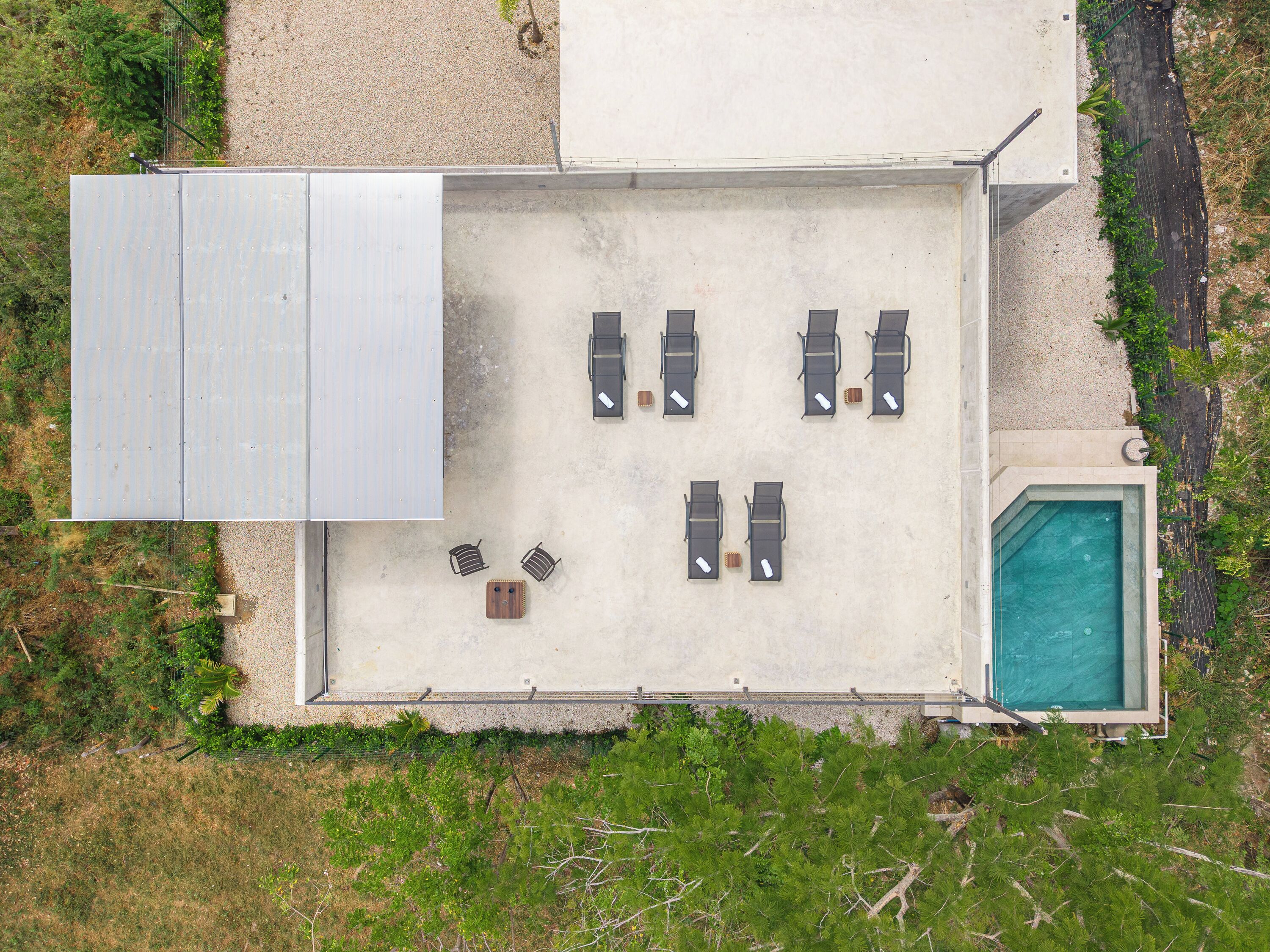 An aerial view of a poolside area with six lounge chairs, a small table, and a pool.