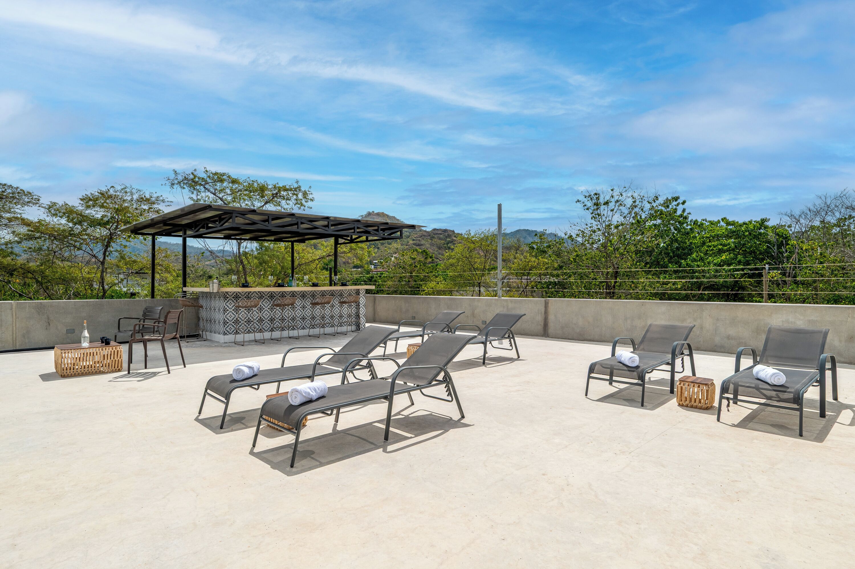 A rooftop terrace with sun loungers, a barbecue area, and a pergola.