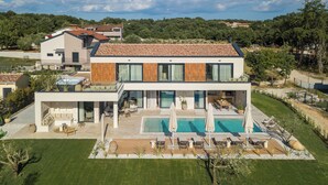 Une maison moderne à deux étages, dotée d’une terrasse sur le toit, d’une piscine et d’un jardin bien entretenu.