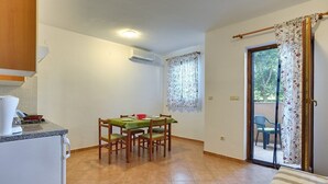 A compact kitchen with a dining table and chairs, a small refrigerator, and a sliding glass door leading to an outdoor area. - Apartments Ulika (16031-A1) - Medulin (Medulin)
