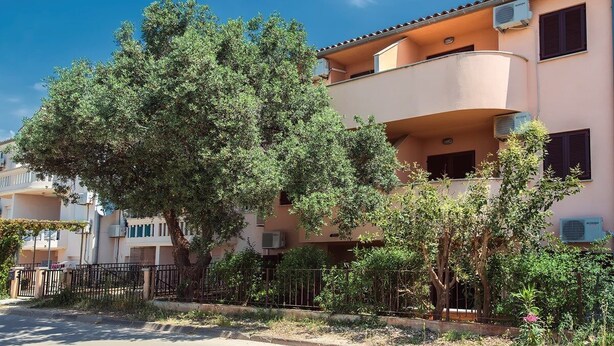 A multi-story building with balconies, air conditioning units, and a tree in the foreground. - Apartments Ulika (16031-A1) - Medulin (Medulin)