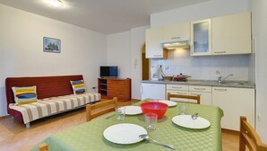 A compact living space with a kitchenette, a sofa, a dining table, and a television. - Apartments Ulika (16031-A1) - Medulin (Medulin)