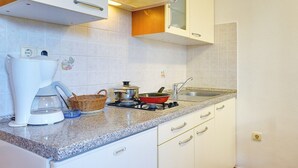 A kitchen with white cabinets, a built-in microwave, a gas stove, and a coffee maker. - Apartments Ulika (16031-A1) - Medulin (Medulin)