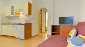 A compact room with a kitchenette, a bed with colorful bedding, and a television. - Apartments Ulika (16031-A2) - Medulin (Medulin)