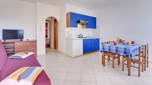 Un espace de vie compact comprenant un coin cuisine, un coin repas et un espace détente avec un téléviseur et un canapé.