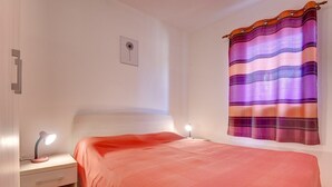 A bedroom with a bed, bedside lamps, a nightstand, a wall-mounted picture, and a striped curtain. - Apartments Ulika (16031-A4) - Medulin (Medulin)