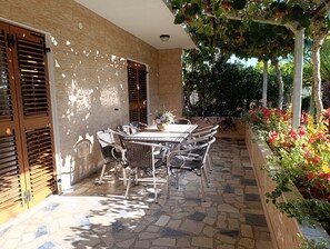 Um pátio com mesa e cadeiras, um muro de tijolos e um jardim com flores.