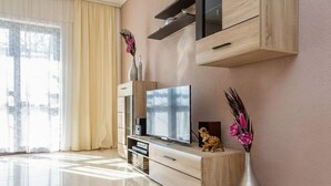 Una sala de estar moderna con televisor de pantalla plana, muebles de madera y elementos decorativos.