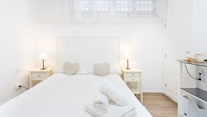 A hotel room with a large bed, two bedside tables with lamps, a window with sheer curtains, and a small desk with a lamp. - Nice sea & pool view apt in Los Cristianos (Los Cristianos)
