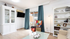 A living room with a glass coffee table, a white cabinet, a sofa, and a television on the wall. - Nice sea & pool view apt in Los Cristianos (Los Cristianos)