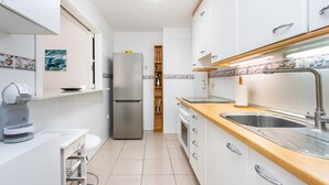 A compact kitchen with white cabinets, a stainless steel refrigerator, a wooden countertop, and a sink. - Nice sea & pool view apt in Los Cristianos (Los Cristianos)