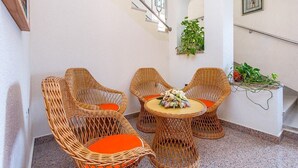 A staircase with a metal railing, wicker chairs with orange cushions, and a small table with a floral arrangement. - Apartments Nevija (16066-A3) - Medulin (Medulin)