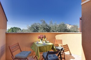 Eine kleine Terrasse im Freien mit einem Tisch für zwei Personen, zwei Stühlen und einer Vase mit Blumen.