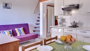 Ein gemütlicher, kleiner Wohnraum mit Sofa, Esstisch und Küchenzeile.