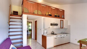 Ein kompaktes Apartment mit Küche, Essbereich und einer Treppe, die zu einer oberen Ebene führt.