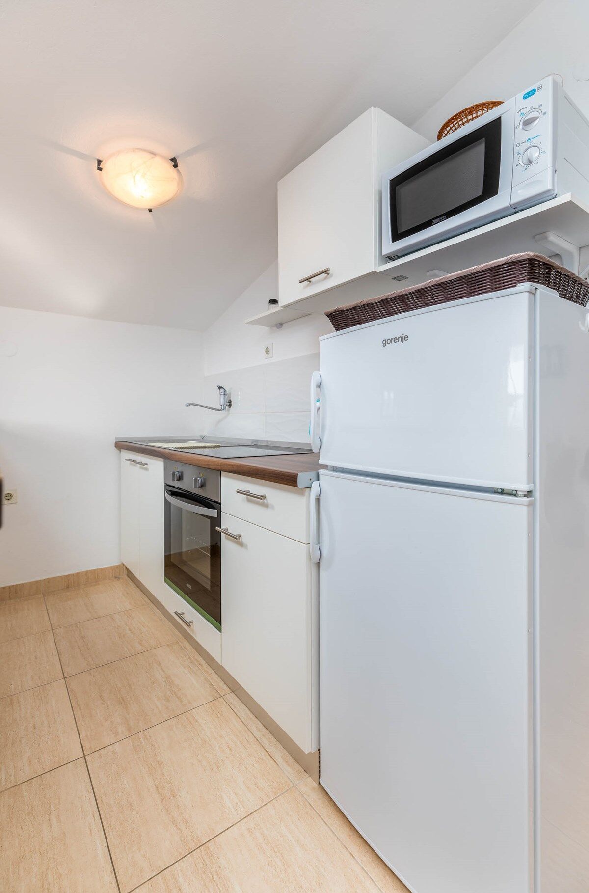A compact kitchen with a microwave, oven, and refrigerator.