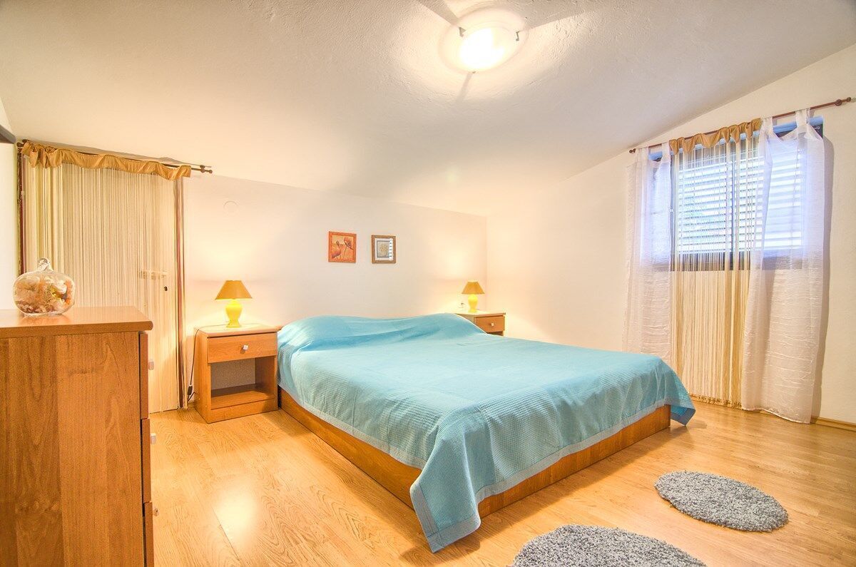Een slaapkamer met een bed, twee nachtkastjes, een kledingkast en een raam met gordijnen.