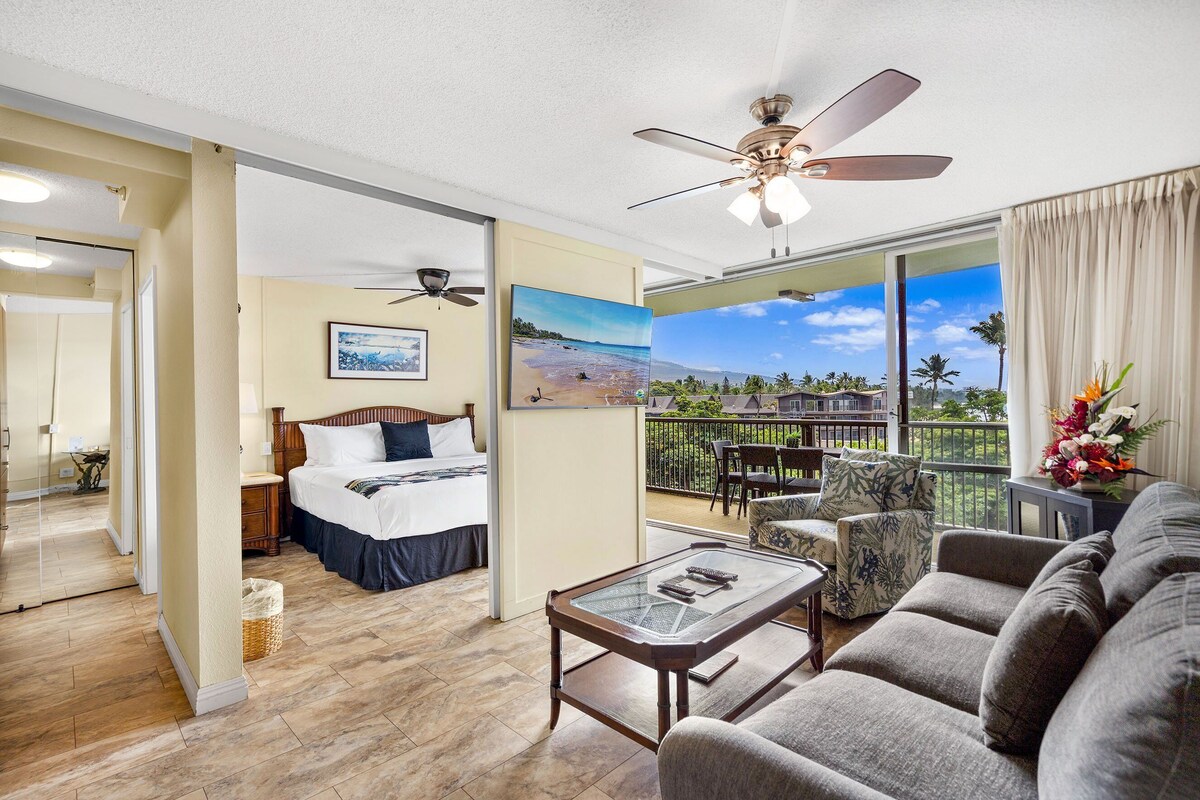 A hotel room with a balcony, a bed, a sofa, and a coffee table.