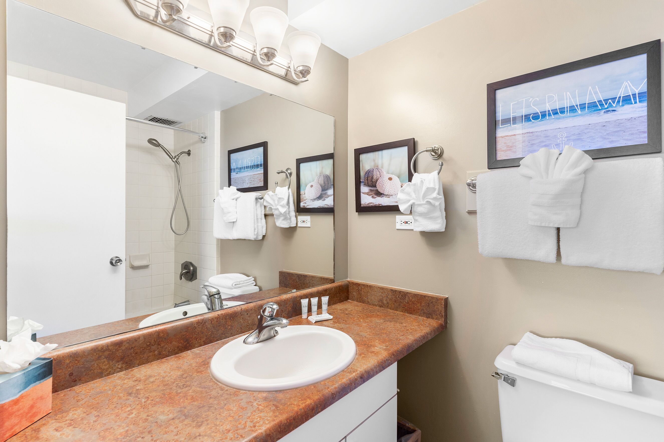 Un bagno con lavandino, specchio, porta asciugamani e un quadro appeso al muro.