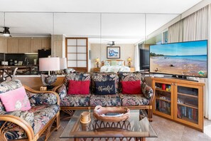 Ein modernes Wohnzimmer mit einer Couch, einem Couchtisch und einem Fernseher, der eine Strandansicht zeigt.