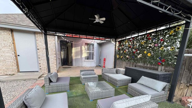 Un patio al aire libre con mobiliario de mimbre y césped artificial.