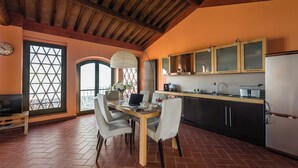 A kitchen with a dining table, chairs, a refrigerator, and cabinets. - Panoramic Appatamento Borgo di Matraia (Matraia)
