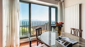 A dining area with a large window, a table with chairs, a vase with flowers, and a view of the mountains. - Panoramic Appatamento Borgo di Matraia (Matraia)