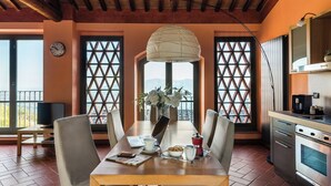 A dining area with a wooden table, chairs, a clock, and a view through lattice windows. - Panoramic Appatamento Borgo di Matraia (Matraia)