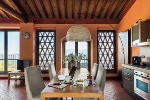 A dining area with a wooden table, chairs, a clock, and a view through lattice windows. - Panoramic Appatamento Borgo di Matraia (Matraia)