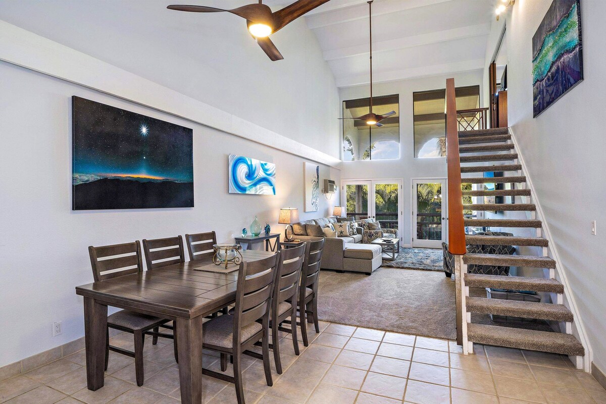 A spacious living area with a dining table, sofas, and a staircase.