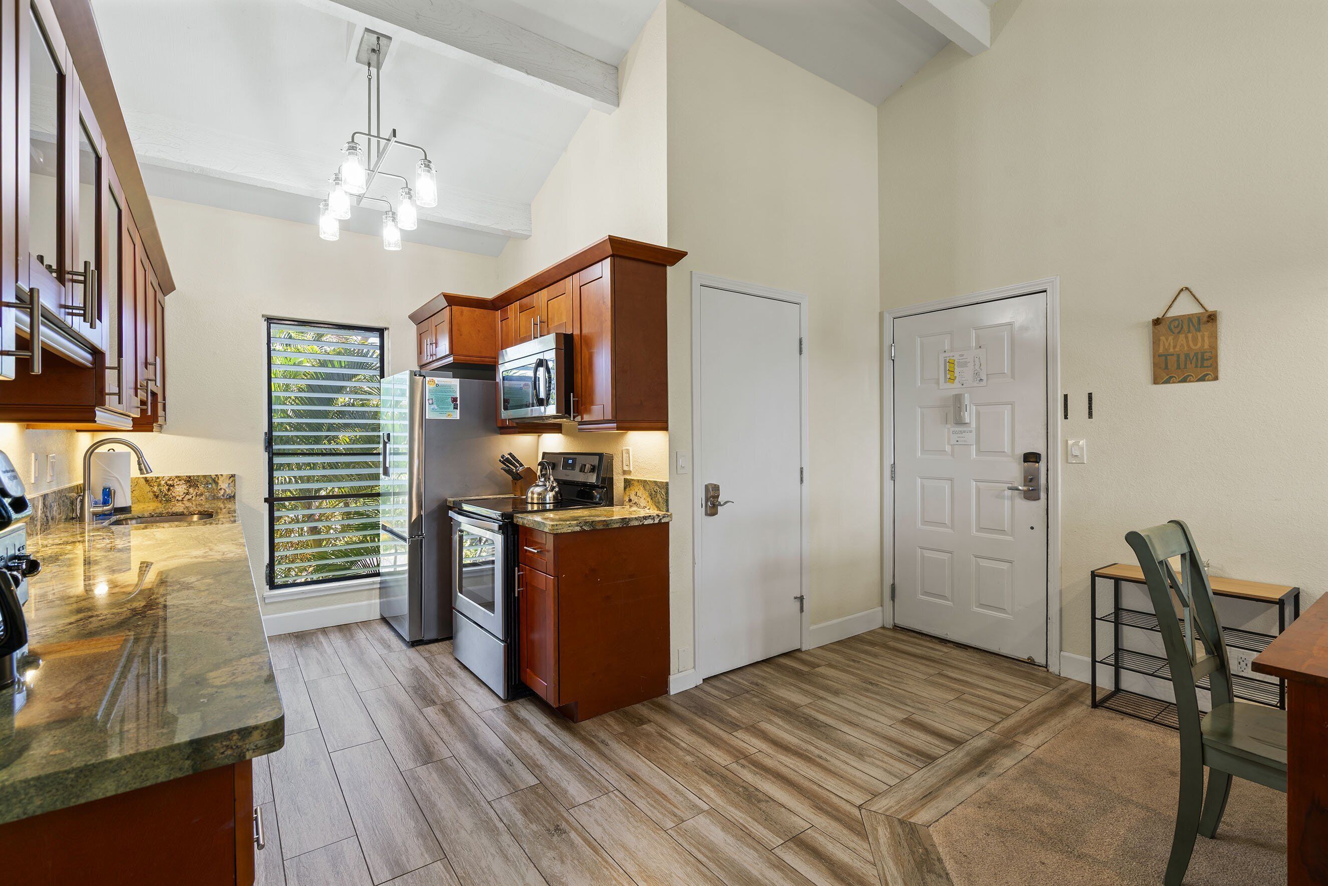A kitchen with wooden cabinets, a microwave, and a stainless steel refrigerator.