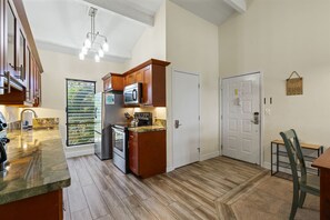 A kitchen with wooden cabinets, a microwave, and a stainless steel refrigerator. - Maui Hill (Kihei)