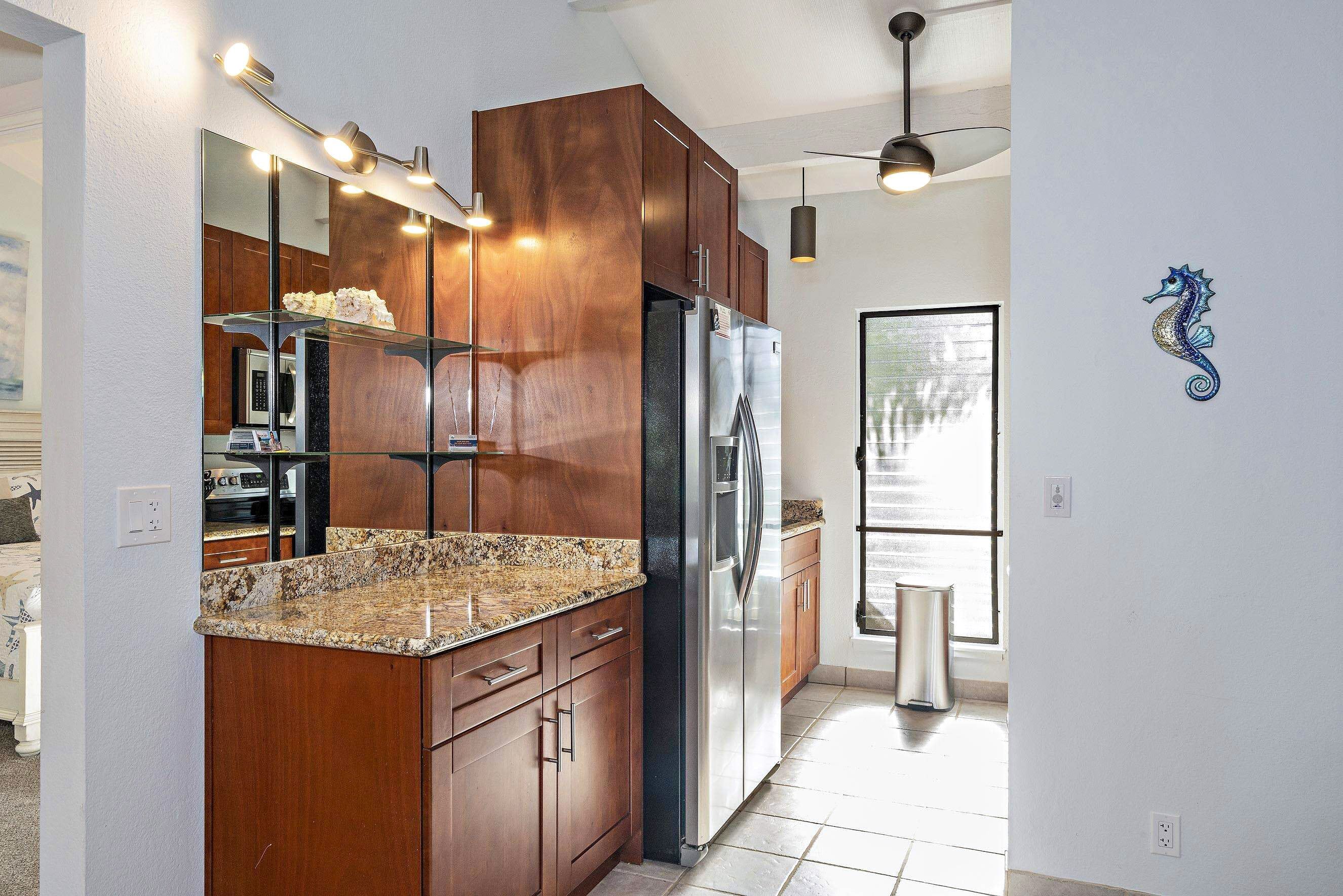 Una cocina moderna con armarios de madera, refrigerador de acero inoxidable, encimeras de granito y horno empotrado.