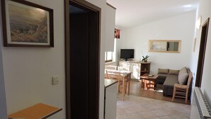 Una sala de estar con sofá, televisión y comedor con mesa y sillas.