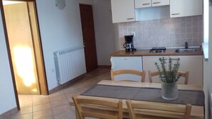 Una pequeña cocina con una mesa y sillas, una cafetera y una planta en maceta.