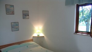 Ett sovrum med en säng, ett nattduksbord med en lampa och tre inramade tavlor på väggen.