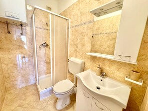 Ein Badezimmer mit Dusche, Toilette, Waschbecken und einem Spiegelschrank.