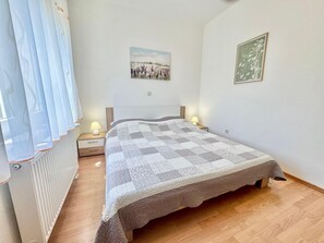 Ein Schlafzimmer mit einem Bett, zwei Nachttischlampen, einer Heizung und zwei Wandbildern.
