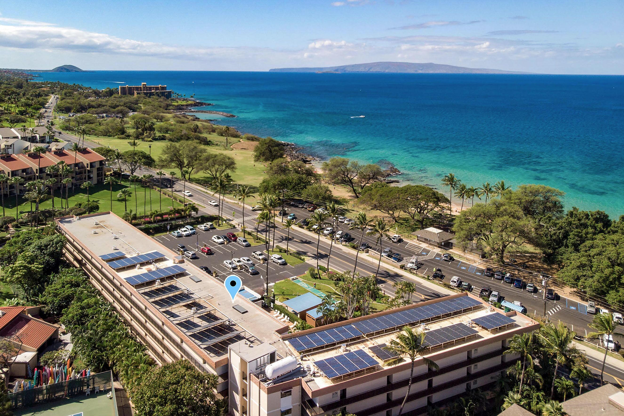 Hotel com vários andares, painéis solares no telhado e vista para o oceano.