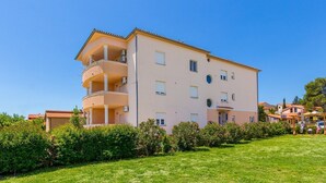 Un edificio de varios pisos con balcones, techo plano y un césped bien cuidado.