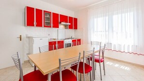 Una cocina moderna con armarios rojos, una mesa de comedor de madera y cuatro sillas rojas.