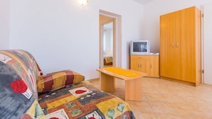 Un dormitorio con cama, televisor, armarios de madera y una puerta.