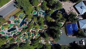 An aerial view of a golf course with multiple greens, water hazards, and a parking area.