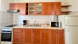 A kitchen with wooden cabinets, a stove, a microwave, and a refrigerator. - Apartments Cukon (16136-A7) - Medulin (Medulin)