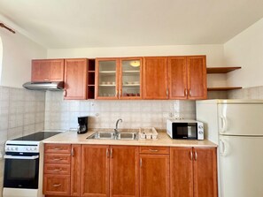A kitchen with wooden cabinets, a stove, a microwave, and a refrigerator. - Apartments Cukon (16136-A7) - Medulin (Medulin)